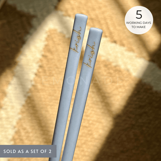 A pair of pastel-colored chopsticks with personalized cursive engraving