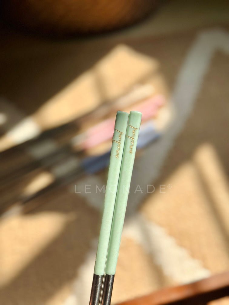 Close-up of stainless steel chopsticks featuring a delicate cursive engraving of the name 