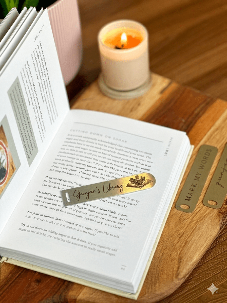 A close-up shot of an engraved gold-toned metal page marker strip resting across the pages of a novel