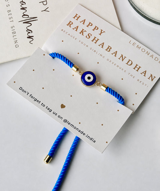 Mini Evil Eye Rakhi with a blue evil eye charm on a braided blue and white thread, handcrafted for Raksha Bandhan gifting